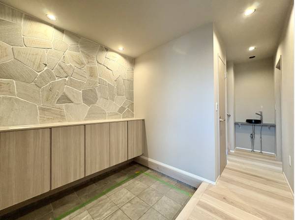 玄関もゆったりスペース。石張りが空間を引き締めます。洗面も完備