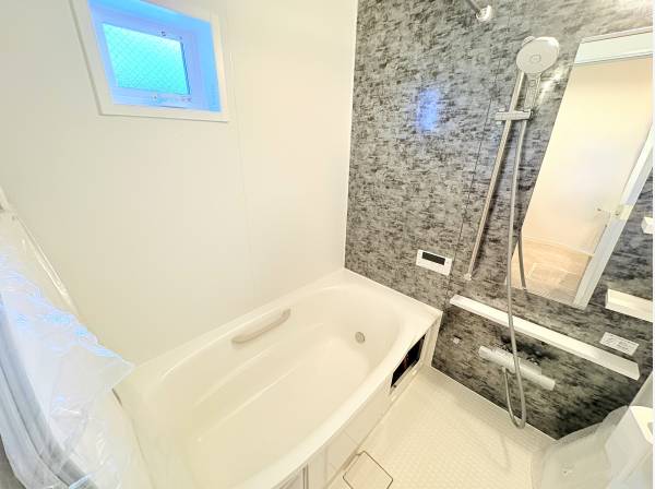 清潔感のある白いバスルームに、石目調の壁がモダンなアクセント