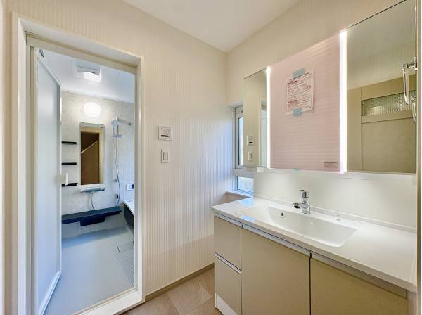 洗面室は白を基調とした清潔感のある空間。三面鏡の裏には十分な収納