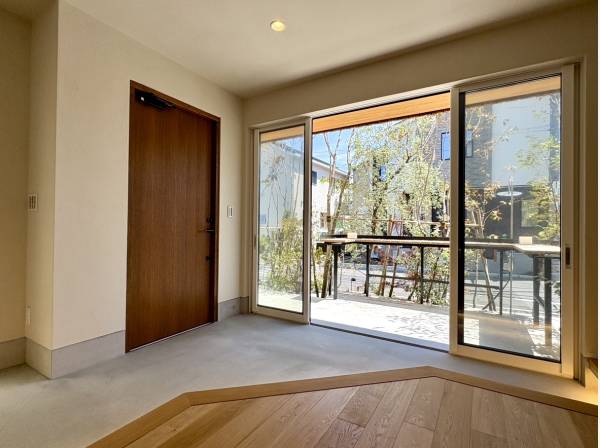 玄関扉と土間、そして外の植栽が調和し、穏やかな空気をつくり出しています