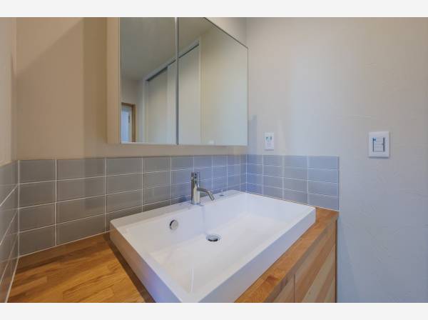 木の質感とタイルが調和する洗面空間。シンプルでありながら上質さを感じるデザイン設計。