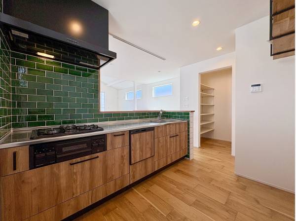 グリーンタイルがおしゃれなキッチン横には広いパントリーも