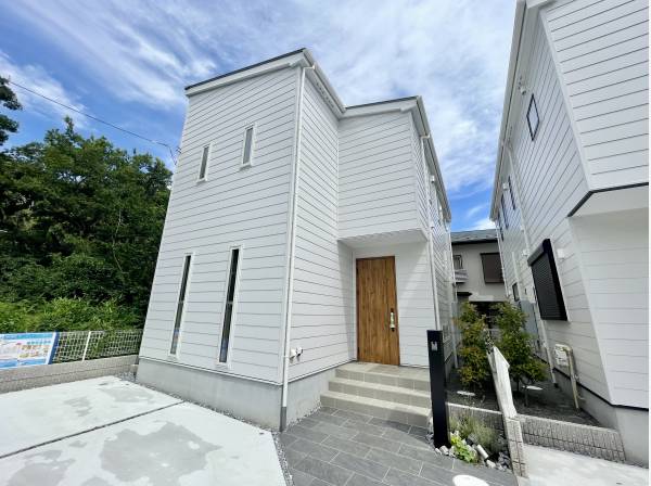 角地の緑と調和する白基調の外観