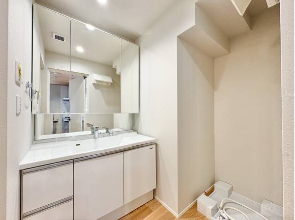 洗面室は白を基調とした清潔感のある空間。三面鏡の裏には十分な収納