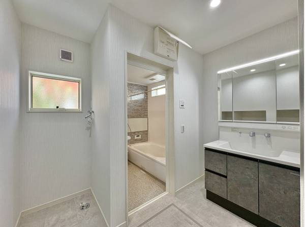 洗面室は白を基調とした清潔感のある空間。三面鏡の裏には十分な収納