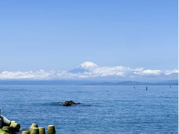 水平線に富士山のシルエット その彼方に夕日が沈みゆくパノラマの景色