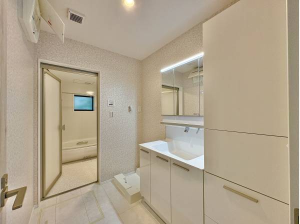 洗面室は白を基調とした清潔感のある空間。三面鏡の裏には十分な収納