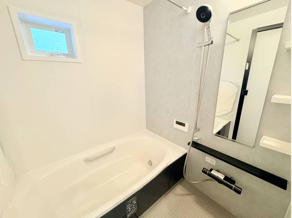 小窓から光が差し込む明るい浴室。モノトーン調で洗練された空間です