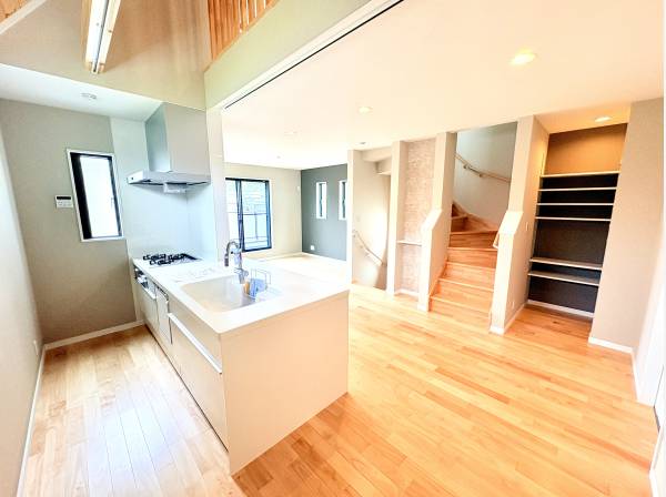 吹き抜けと木の階段が開放感を演出。オープンキッチンが主役です