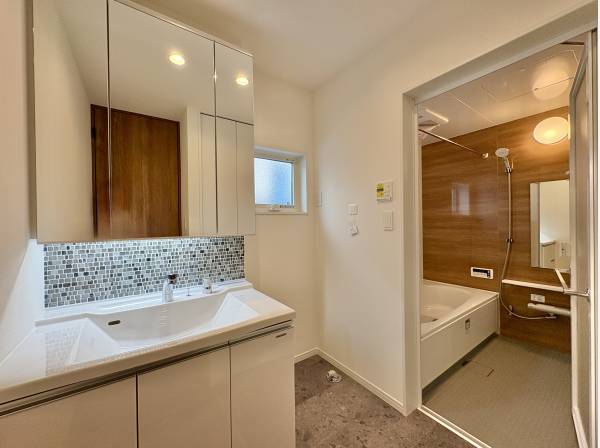 洗面室は白を基調とした清潔感のある空間。三面鏡の裏には十分な収納