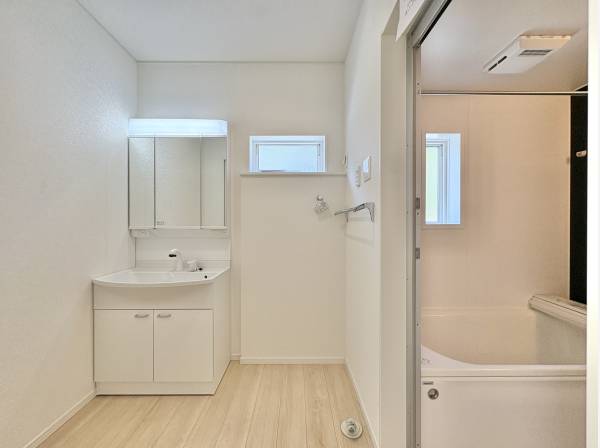 洗面室は白を基調とした清潔感のある空間。三面鏡の裏には十分な収納