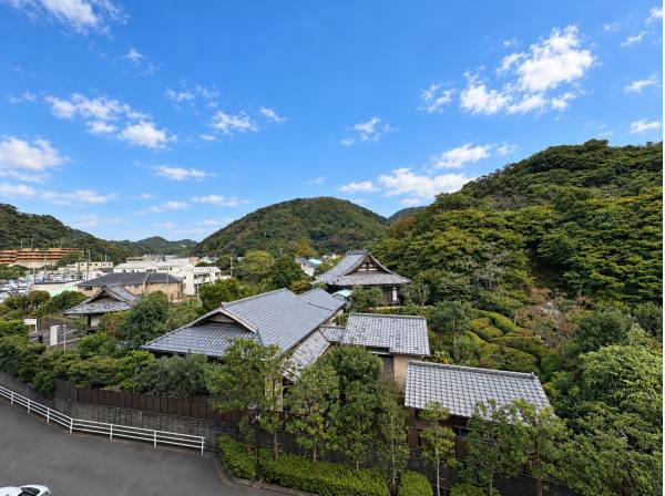 緑豊かな山並みと趣ある瓦屋根を見渡す眺望、青空の下で季節の移ろいを満喫
