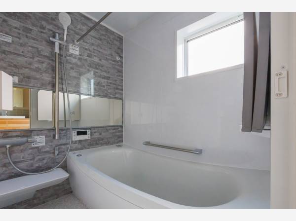 一日の疲れを癒す落ち着いたバスルーム。窓からの光が心地よいリラックス空間を演出。