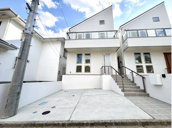 白い外観が空の青さに映え街並みに軽やかな存在感を添える住まい