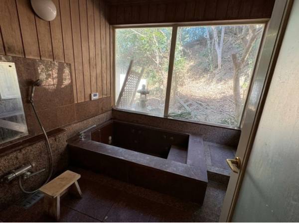 大きな窓から緑を望むゆったりとした石造りのバスルーム