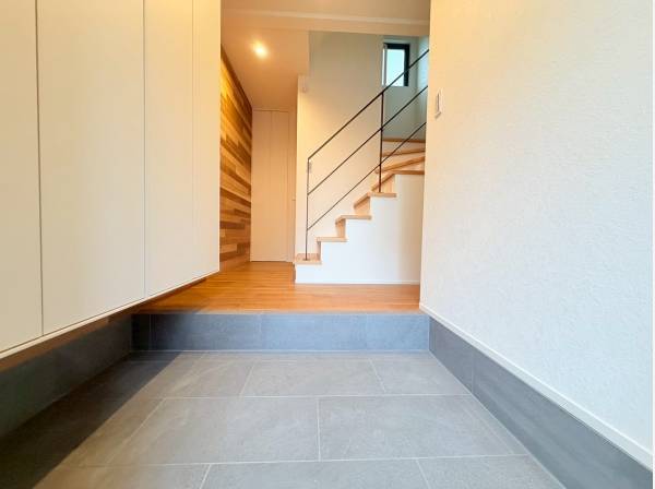 抜け感のある階段に木目調のクロスであたたかいエントランス