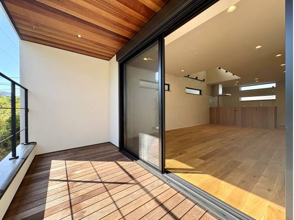 ウッドデッキの敷かれたワイドバルコニーからシームレスにつながるリビング